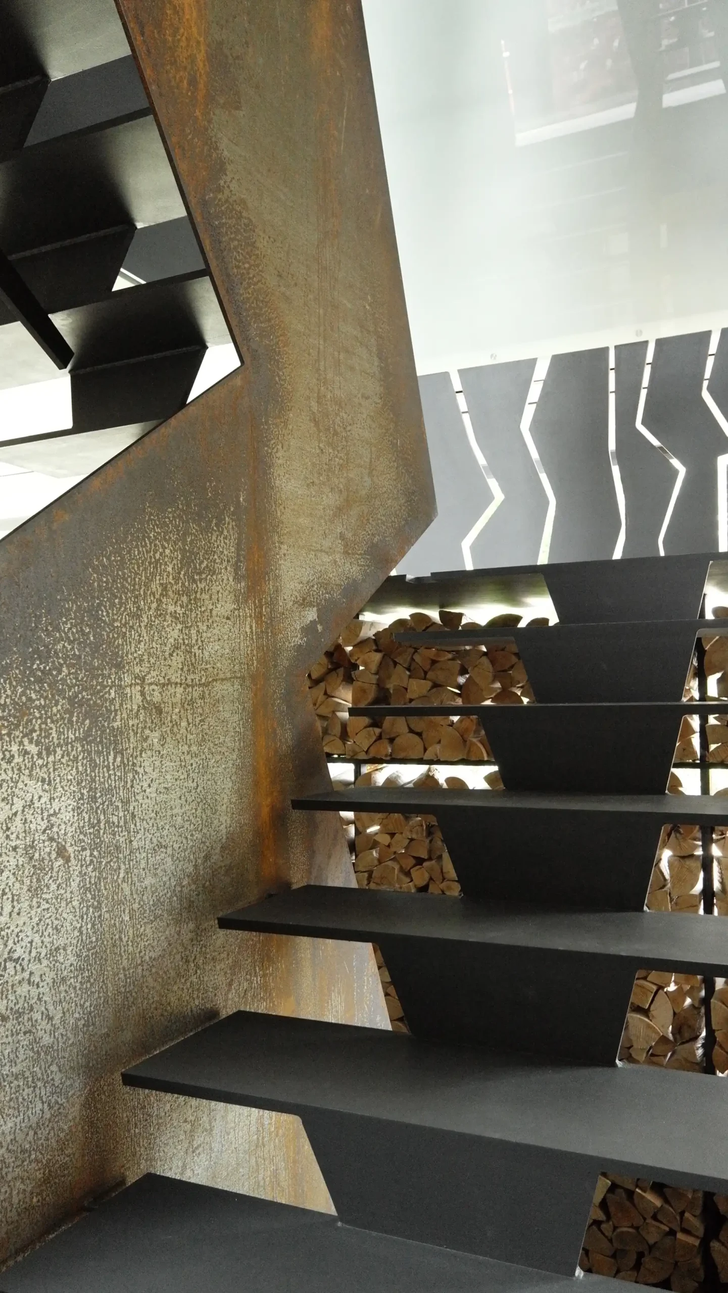 Stahltreppe mit Cortenstahl-Brüstung und Holzlager in der Villa im Hardtwald, Bad Homburg