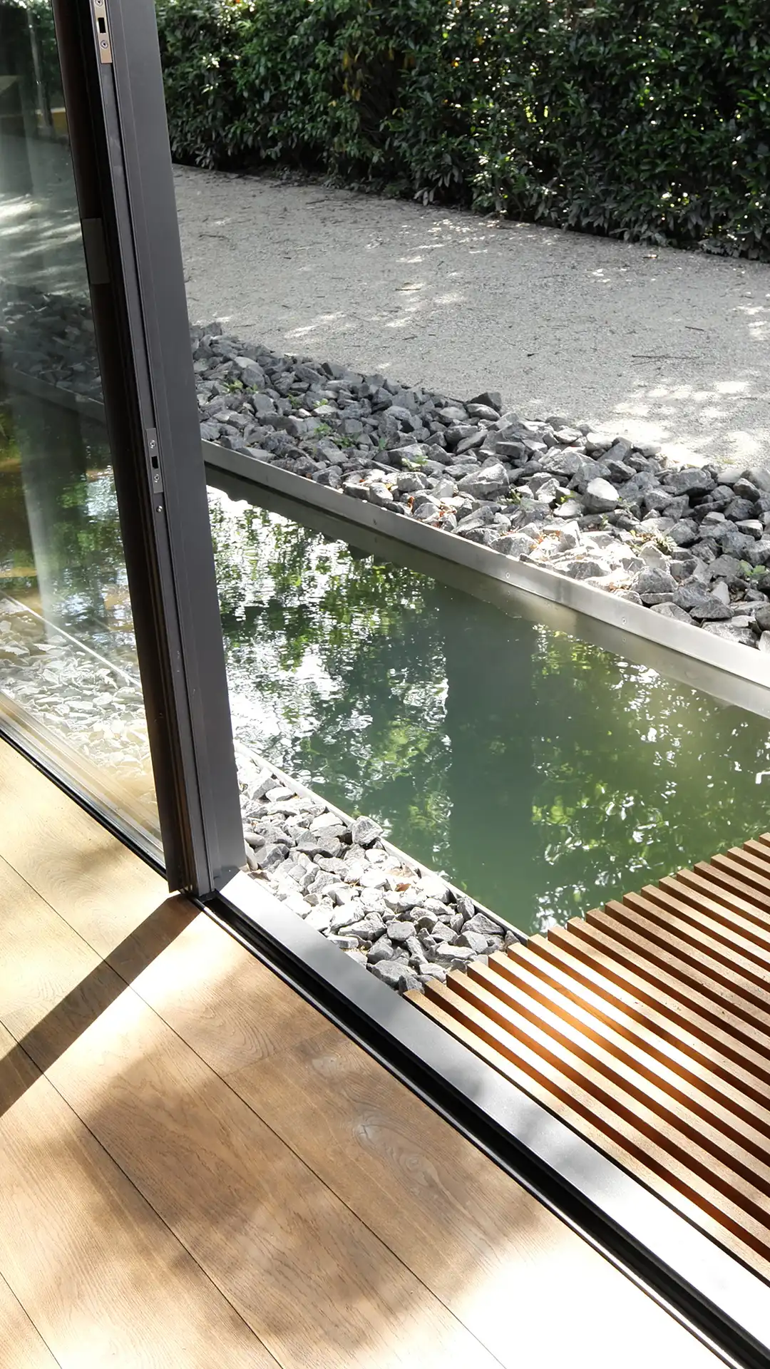 Wasserfläche unmittelbar vor der Glasfassade der Villa im Hardtwald in Bad Homburg mit Übergang von Innenraum zu Außenraum