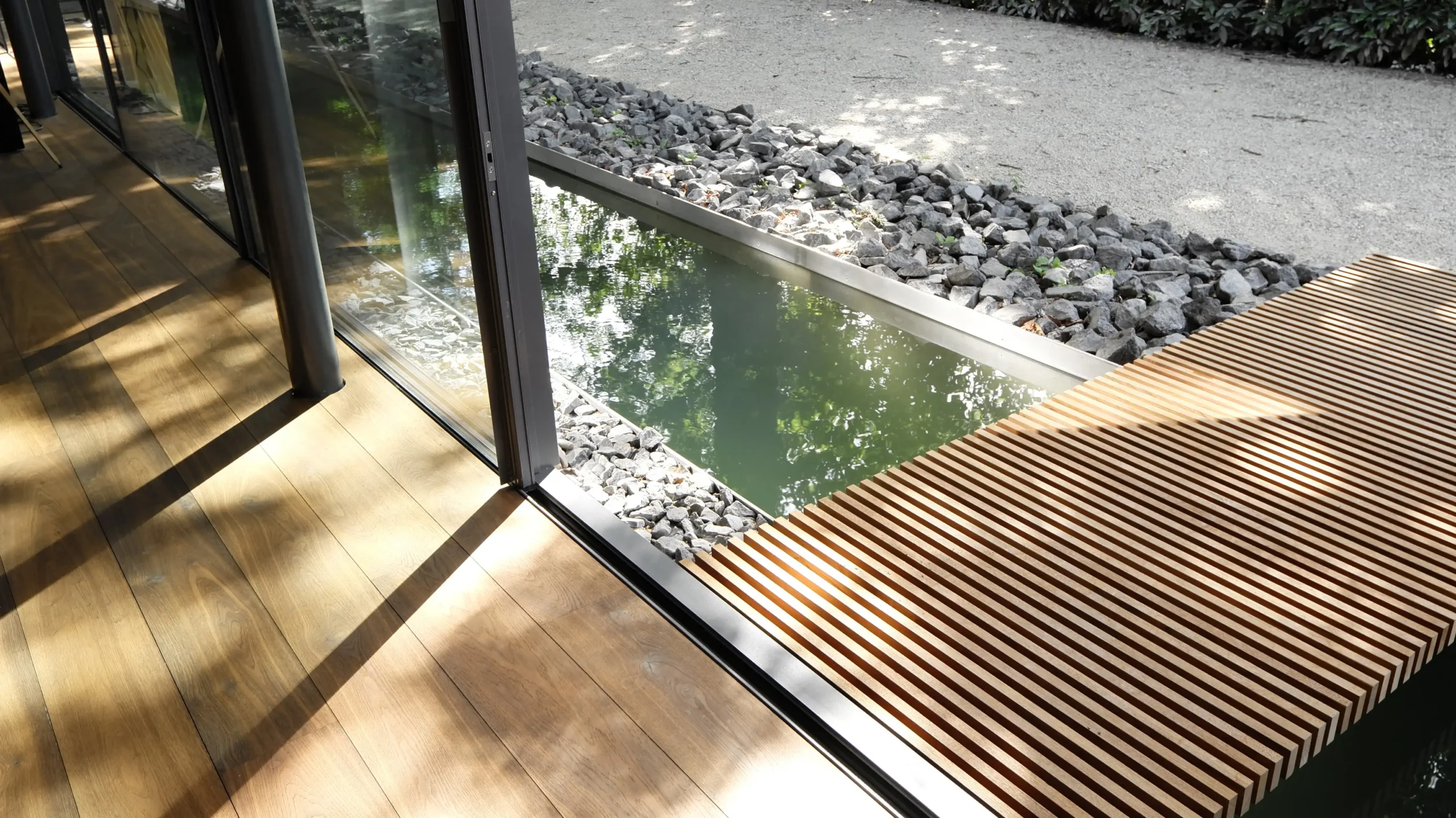 Wasserfläche unmittelbar vor der Glasfassade der Villa im Hardtwald in Bad Homburg mit Übergang von Innenraum zu Außenraum