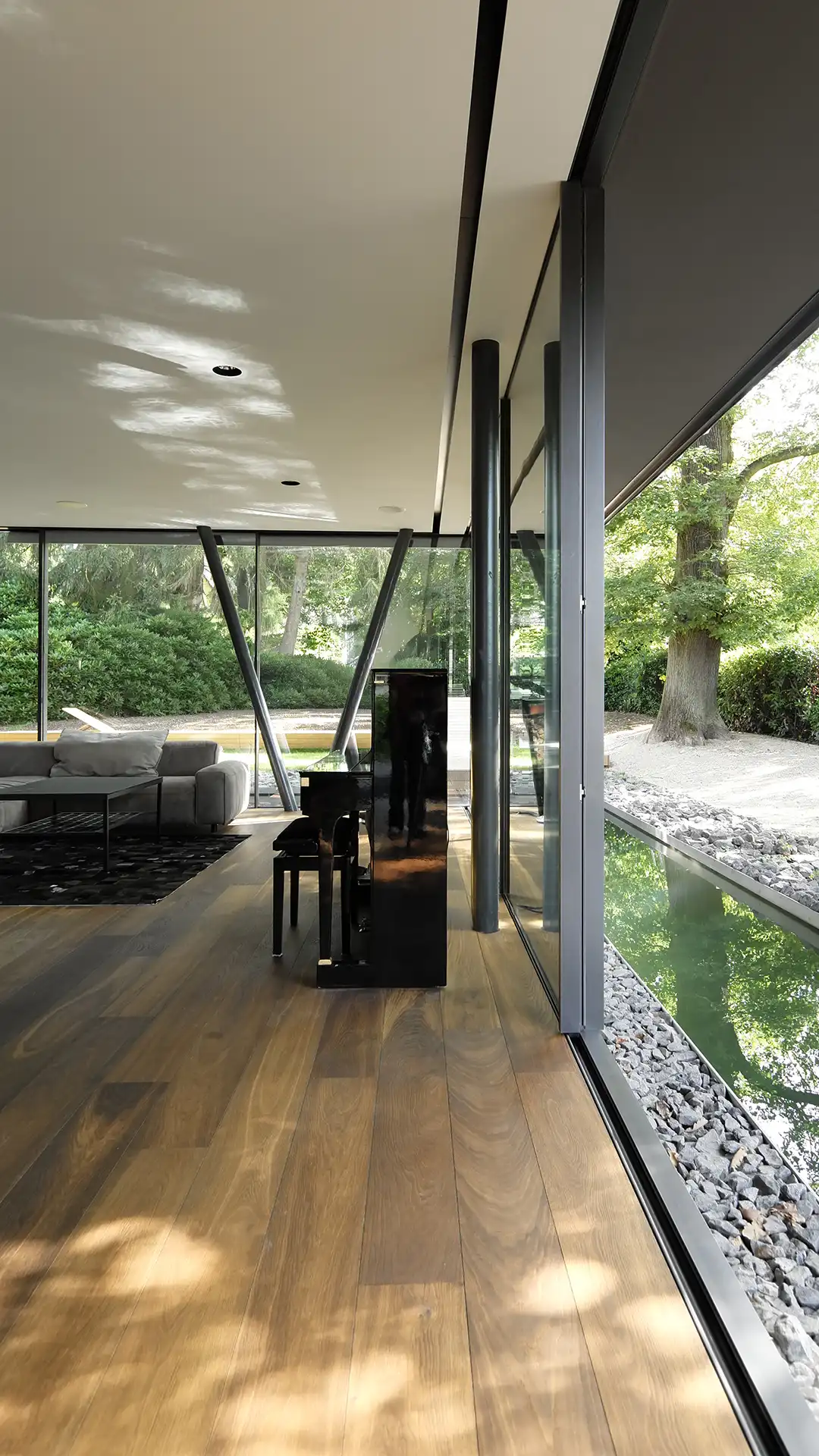 Innenraum der Villa im Hardtwald in Bad Homburg mit bodentiefer Skyframe-Verglasung und Wasserfläche am Wohnraum (hochformat)