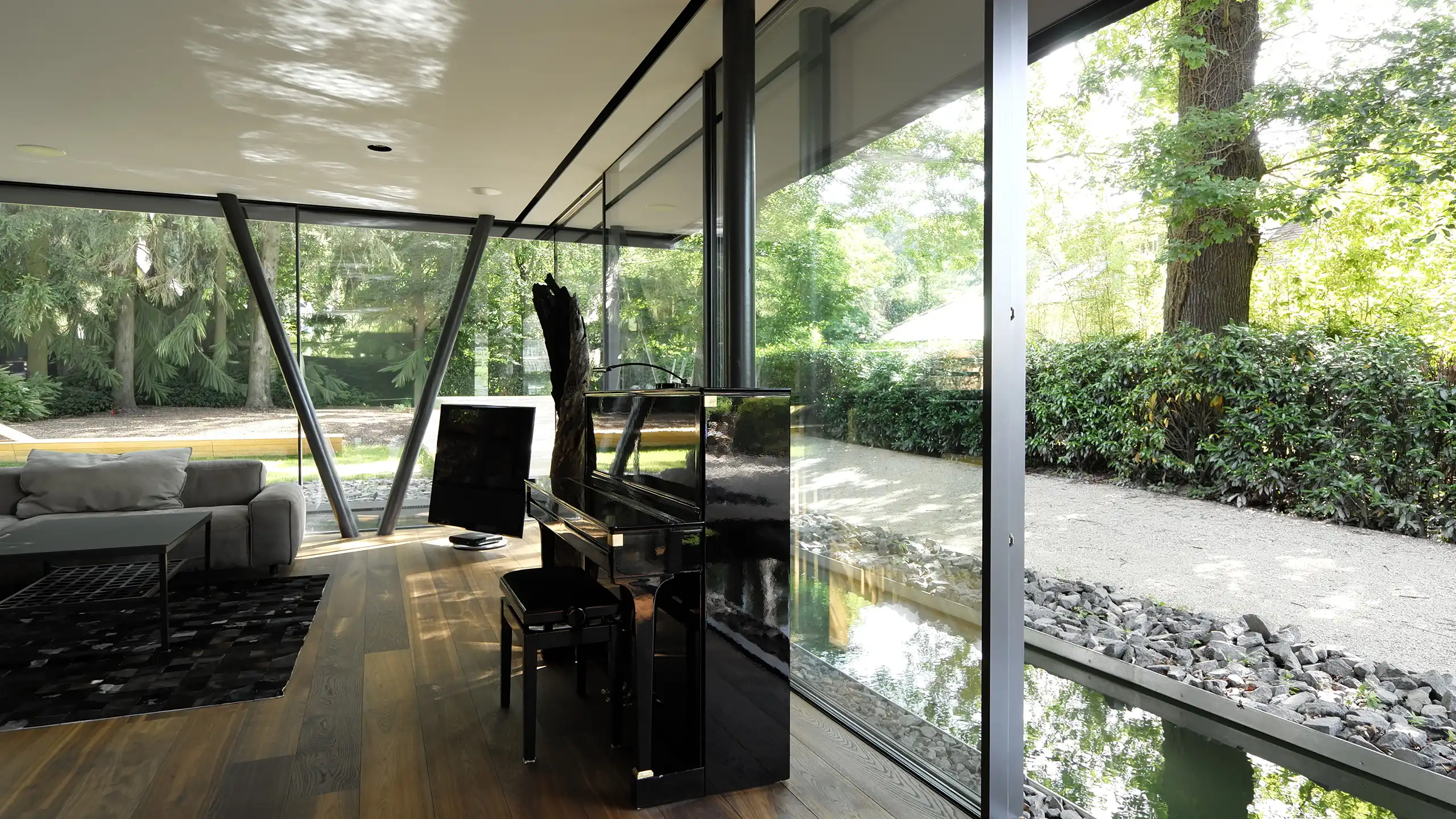 Innenraum der Villa im Hardtwald in Bad Homburg mit bodentiefer Skyframe-Verglasung und Wasserfläche am Wohnraum