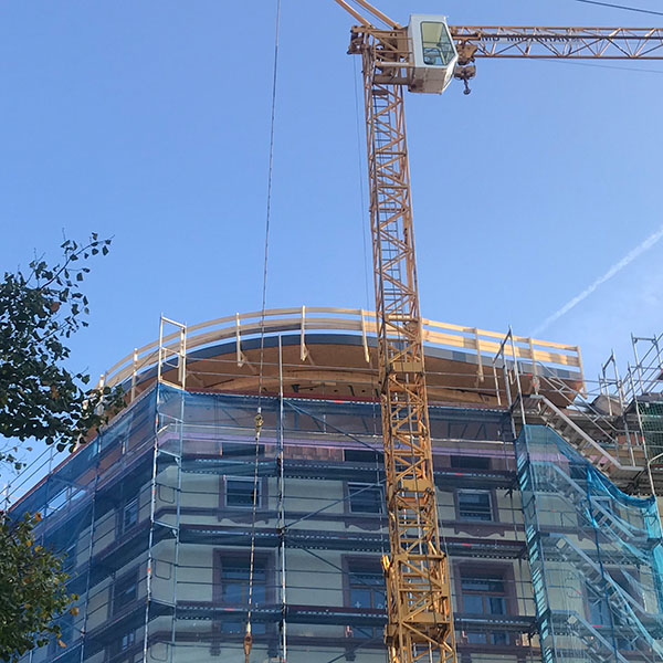 Dachaufstockung im Wasserweg 17 in Frankfurt Sachsenhausen während der Holzbauarbeiten mit Kran und eingerüstetem Gebäude.