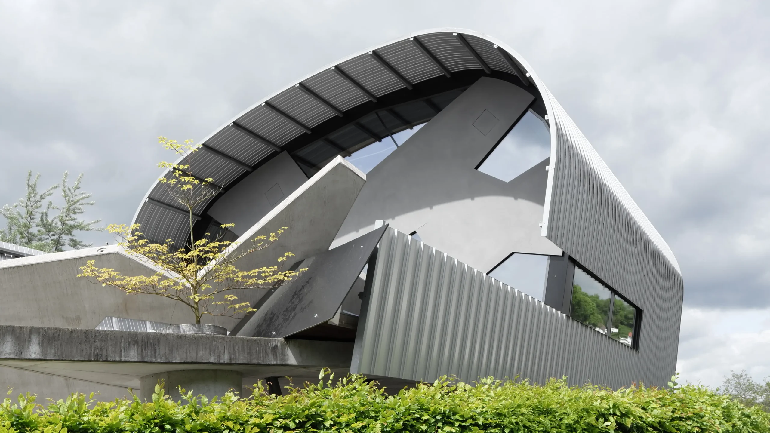 Haus des Markscheiders in Tiefenbach bei Wetzlar von Gronych + Dollega Architekten, Außenansicht mit markanter Bogenform, geneigter Betonwand und großem Fensterband