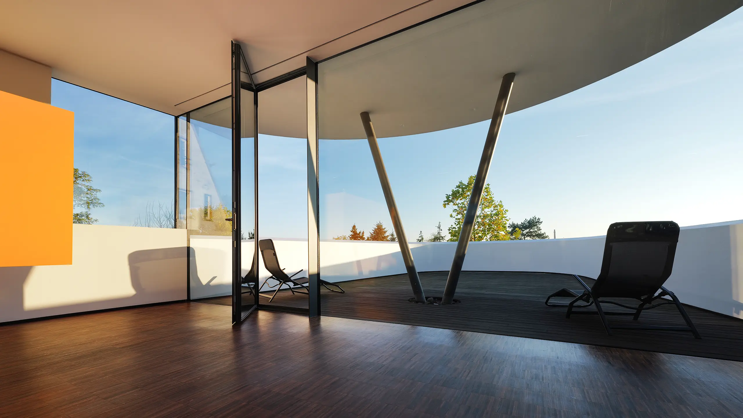 Dachterrasse des Wohnhauses An Steins Garten in Gießen mit geschwungener Decke, raumhoher Verglasung und zwei schrägen Stahlstützen.