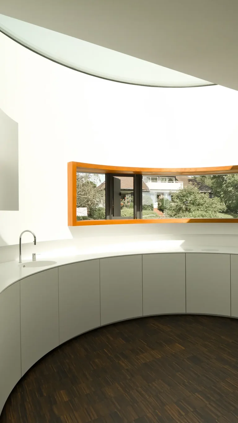 Vertikale Ansicht der gebogenen Küche im Wohnhaus An Steins Garten in Gießen mit Fensterband mit Teakrahmen und Oberlicht.