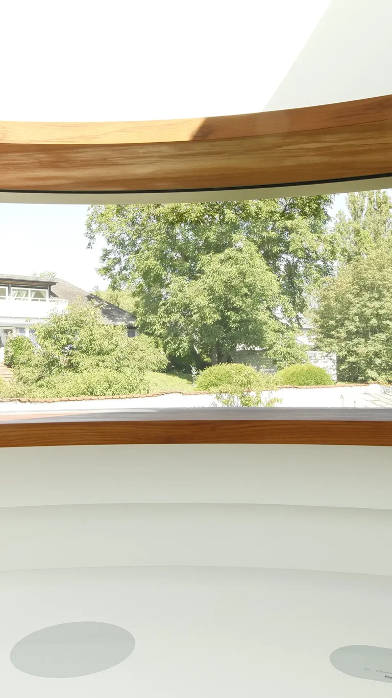 Vertikales Detail der gebogenen Küche im Wohnhaus An Steins Garten in Gießen mit Corian-Arbeitsfläche und Fensterband mit Teakrahmen.
