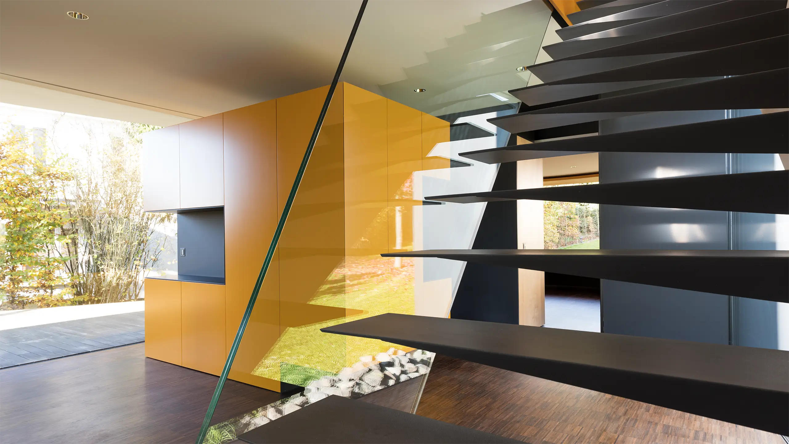 Stahltreppe mit Kragstufen im Eingangsbereich des Wohnhauses An Steins Garten in Gießen, im Hintergrund die gelbe Garderobe.
