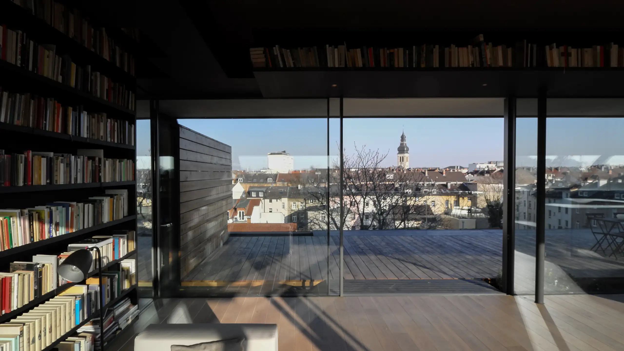 Bücherwand im Dachgeschoss des Wilhelmsplatz 16 in Offenbach mit Blick durch das geöffnete Sky-Frame zur Dachterrasse